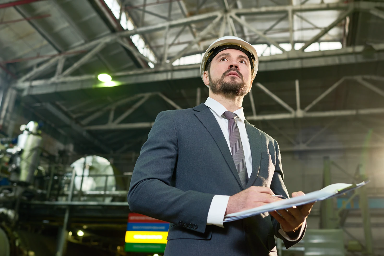 Industrial engineer in a hard hat conducting a facility inspection and safety audit at a manufacturing plant