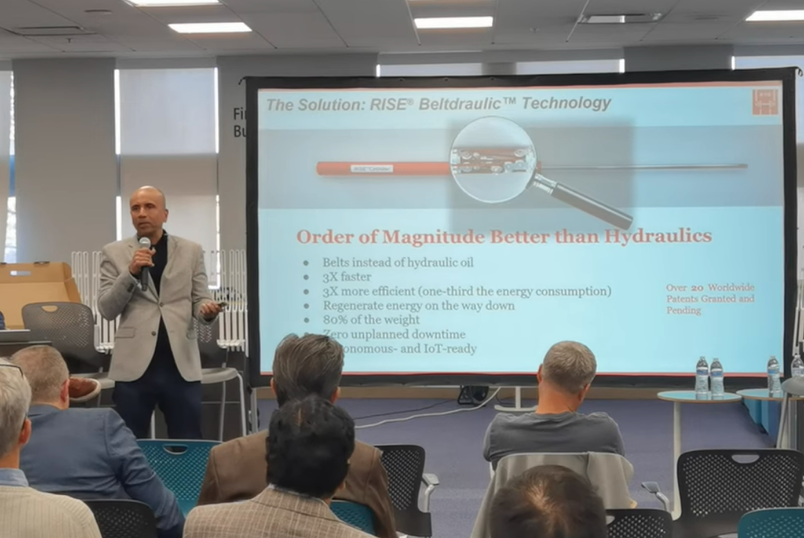 Presenter explaining the efficiency advantages of an energy-regenerating Beltdraulic system during a seminar