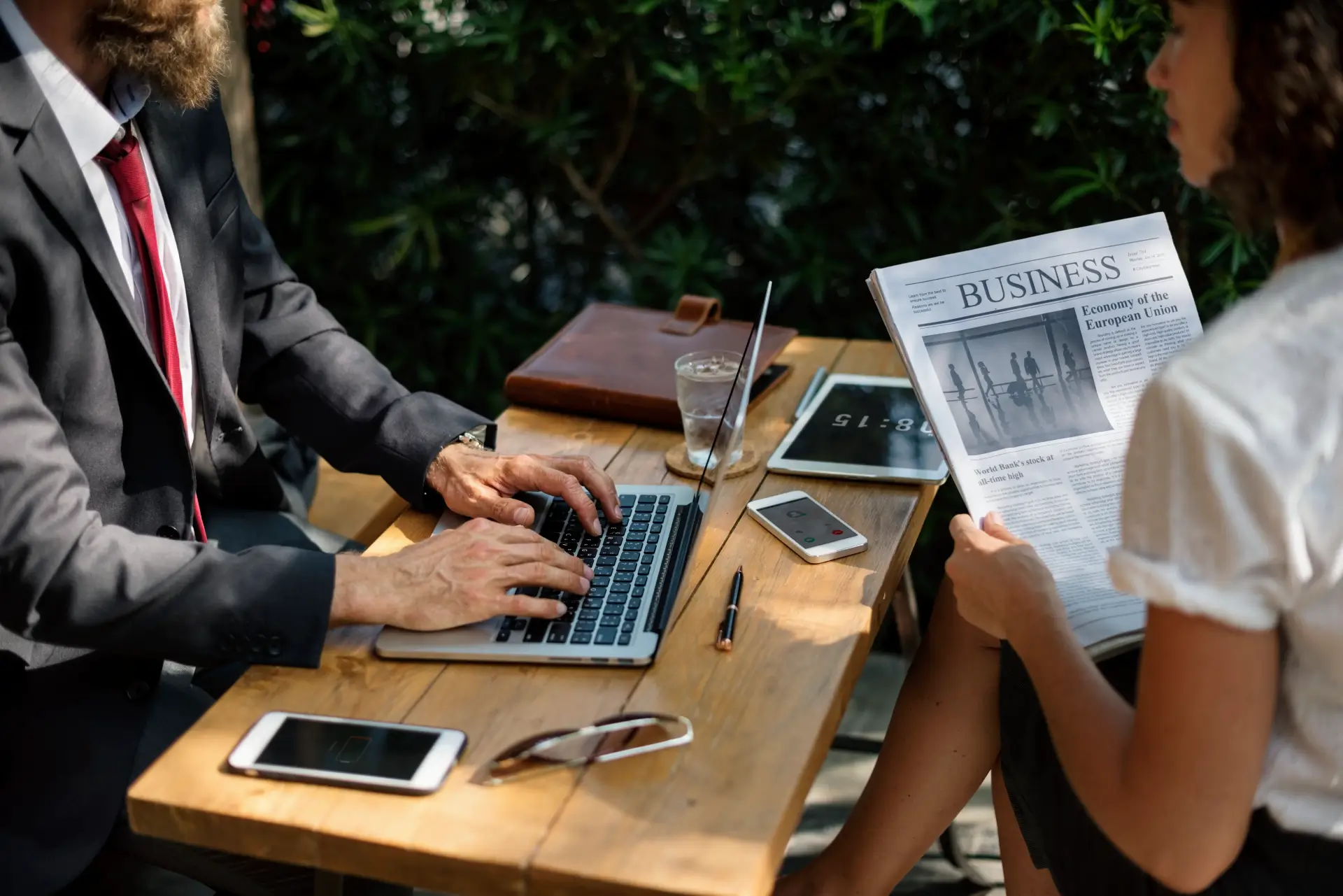 business professionals working with a laptop, smartphone, and newspaper