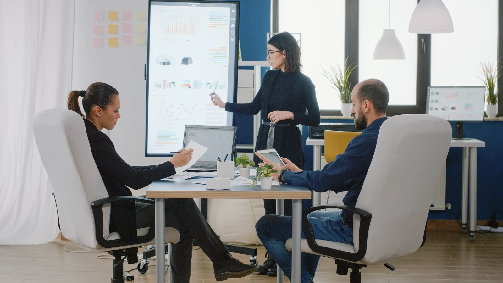 Corporate team evaluating financial growth models and marketing metrics on a digital dashboard screen