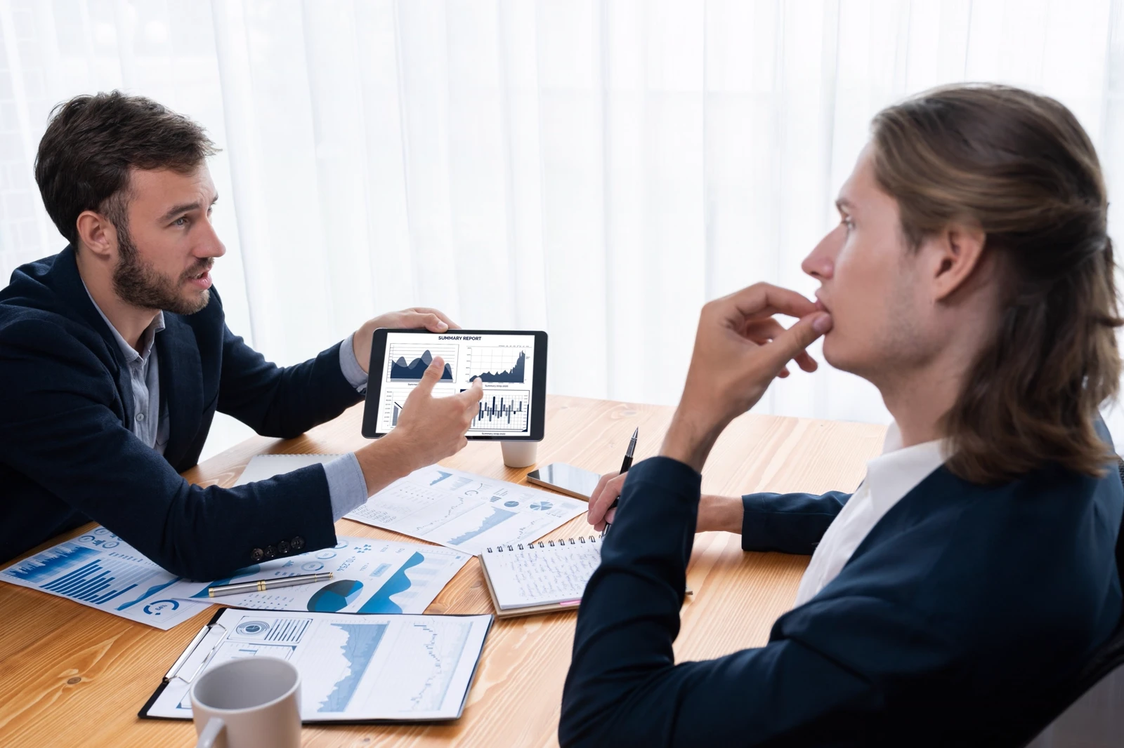 discussing investment portfolio performance and data charts on a digital tablet during a client consultation