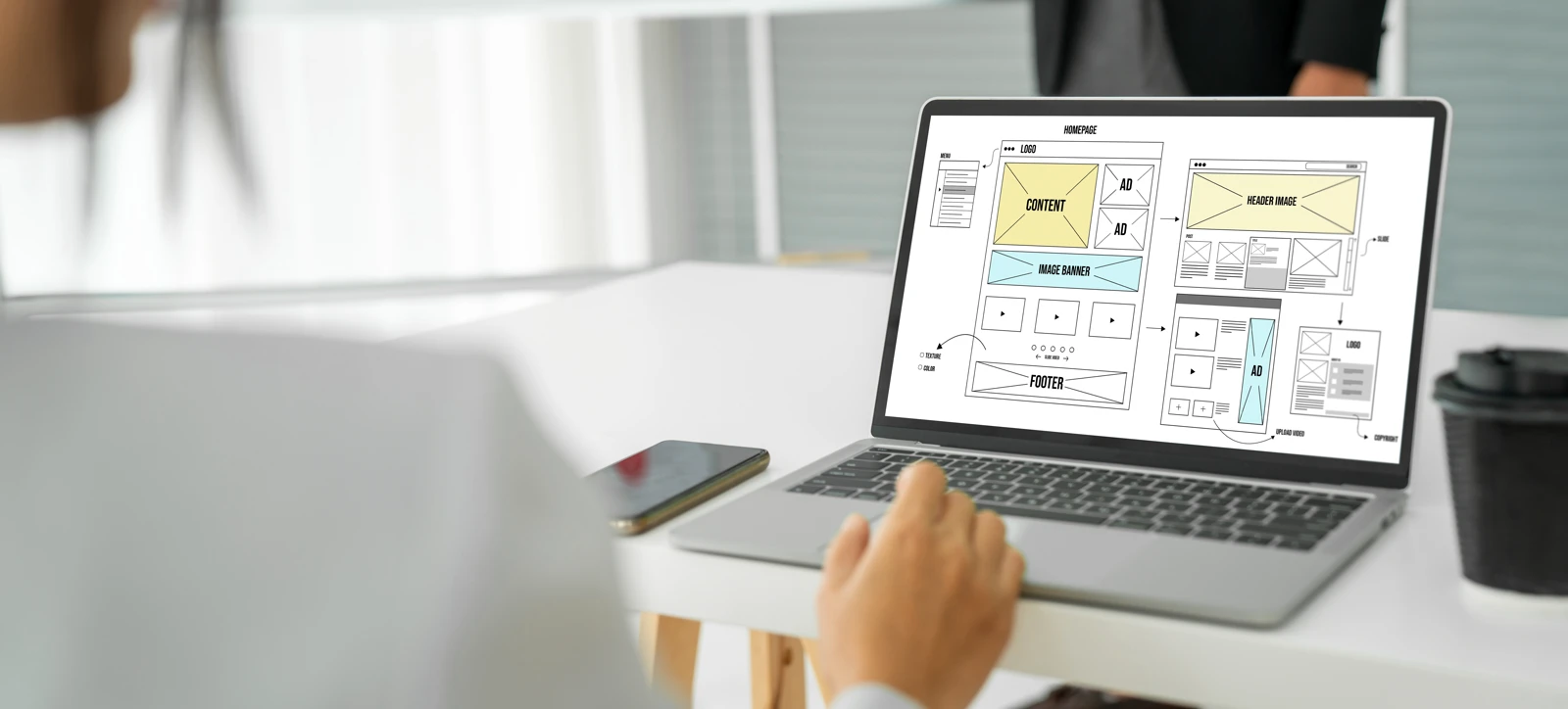 Laptop screen displaying interactive website homepage wireframes and design mockups