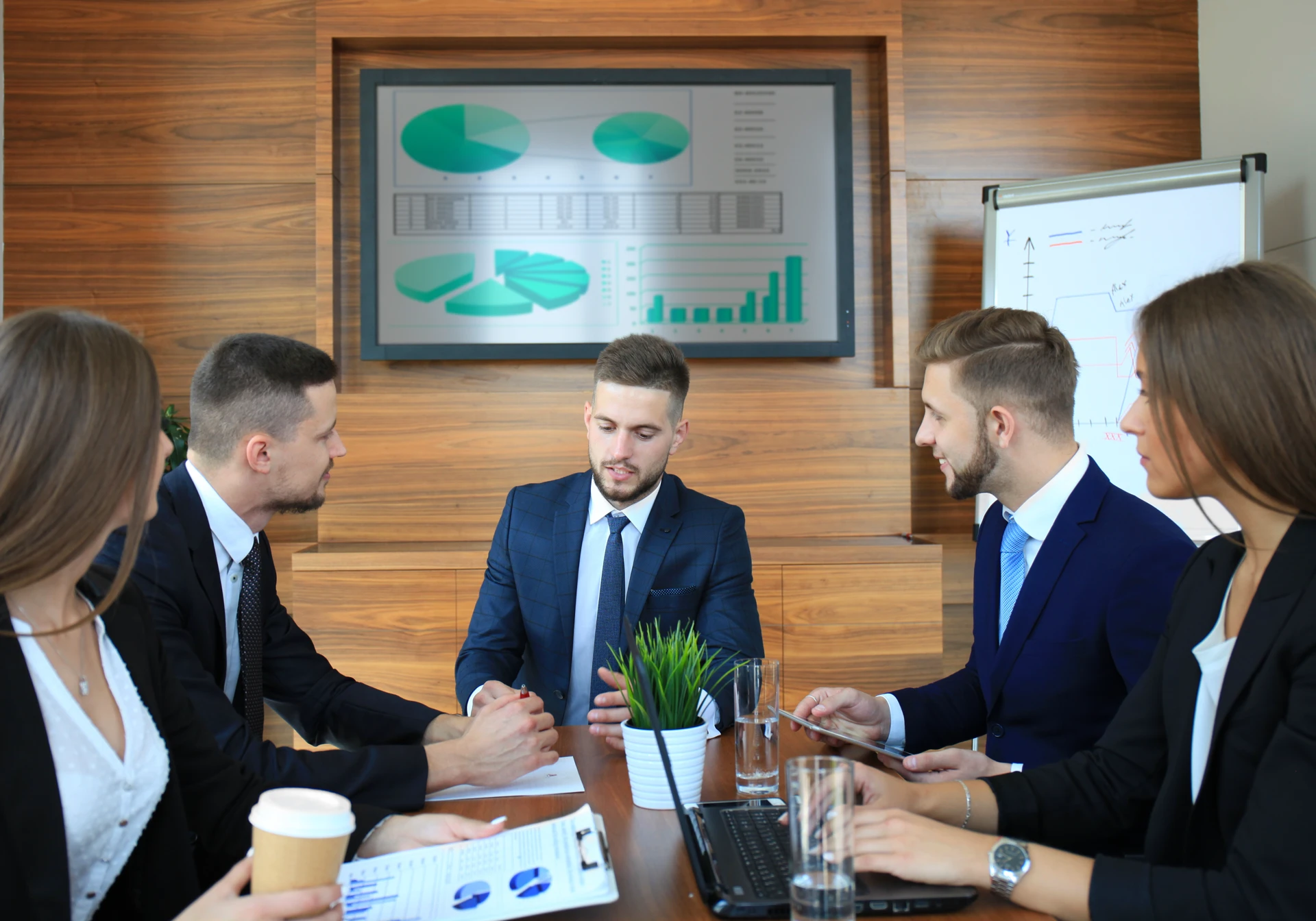 five business professionals gathered around a laptop